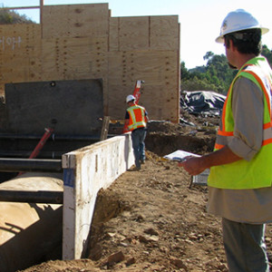 noise monitor watching constuction crew working on large pipeline